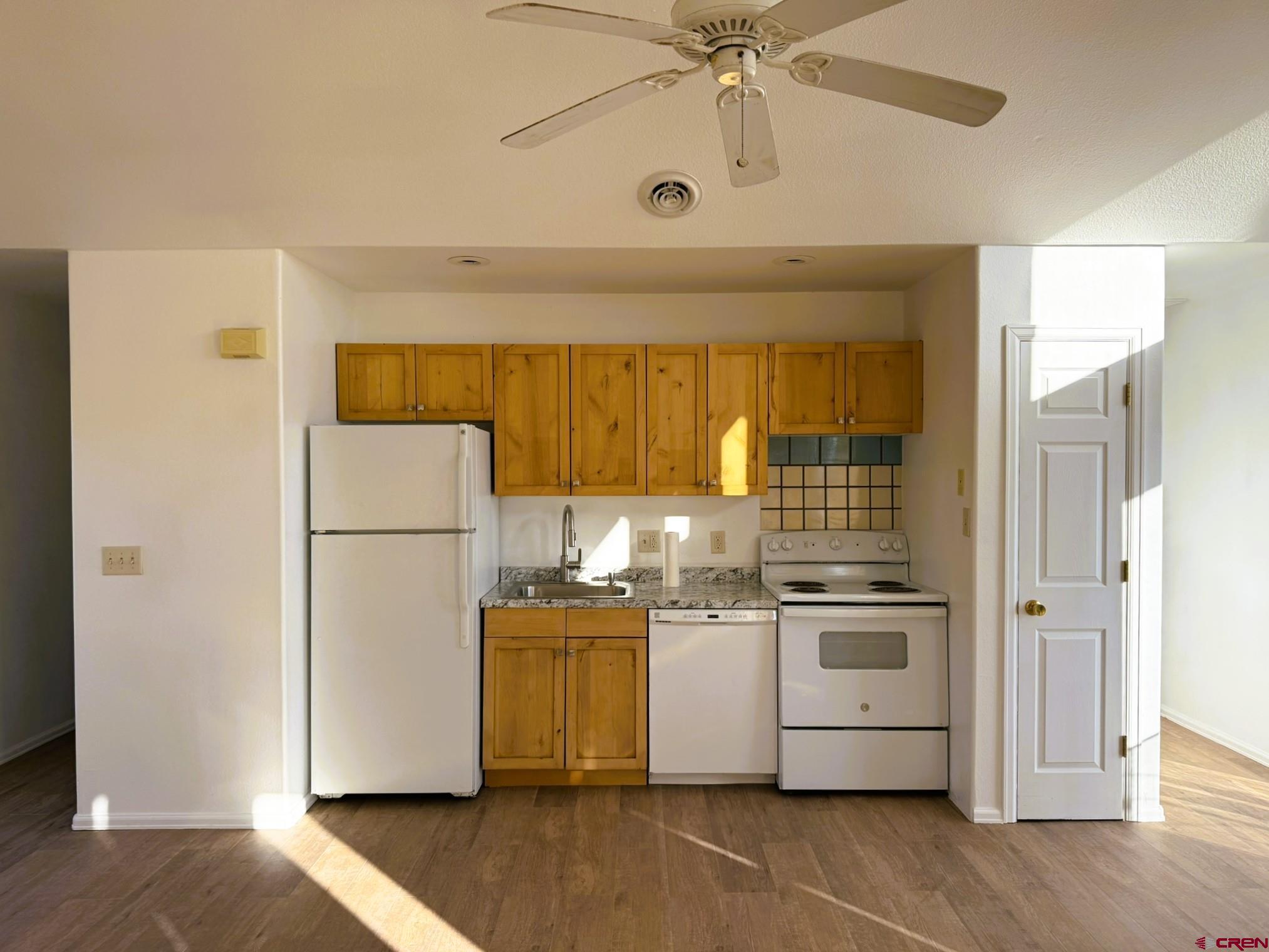 18358 Surface Creek Road Cedaredge, CO 81413 - Photo 4 of 26 a kitchen with a refrigerator a stove and a wooden floor
