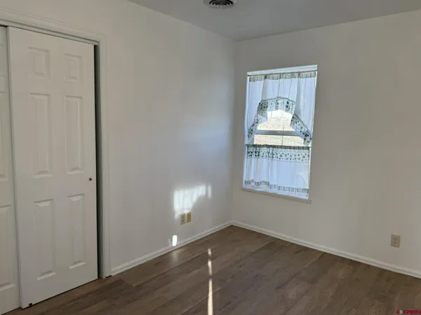 an empty room with wooden floor cabinet and windows