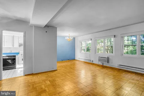 a view of an empty room with window and a kitchen