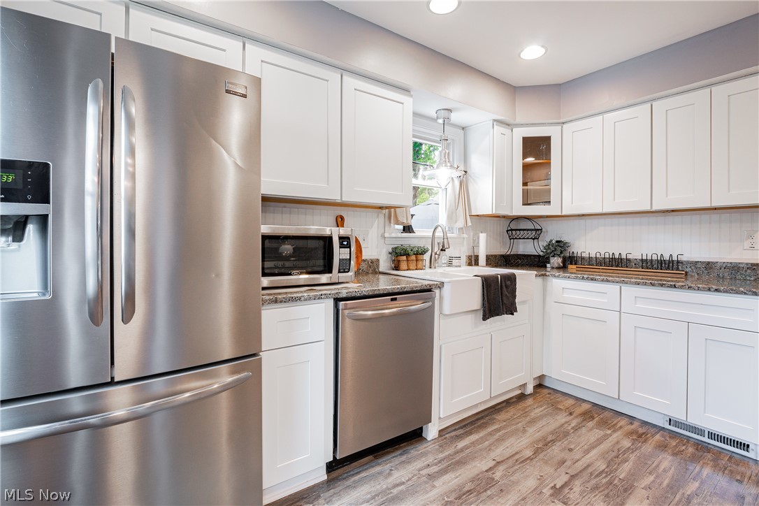 9630 Snow Road Cleveland, OH 44130 - Photo 12 of 31 Kitchen featuring white cabinetry, tasteful backsplash, dark stone countertops, light hardwood / wood-style floors, and appliances with stainless steel finishes