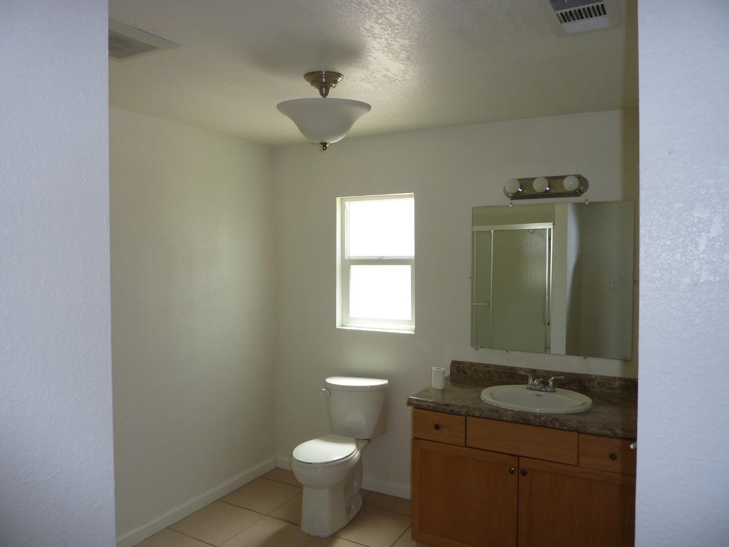 2629 East Richert Avenue Fresno, CA 93726 - Photo 13 of 32 a bathroom with a granite countertop sink a toilet and mirror