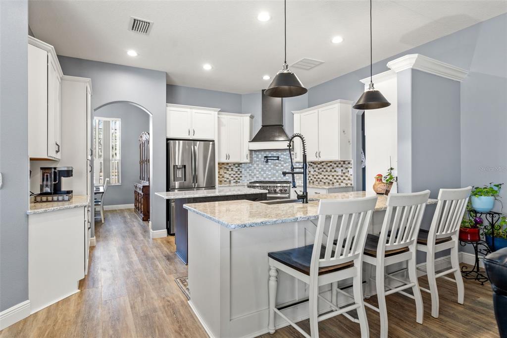 12277 Eskimo Curlew Road Weeki Wachee, FL 34614 - Photo 13 of 84 a kitchen with stainless steel appliances kitchen island granite countertop a stove a refrigerator a oven a sink with a dining table and chairs