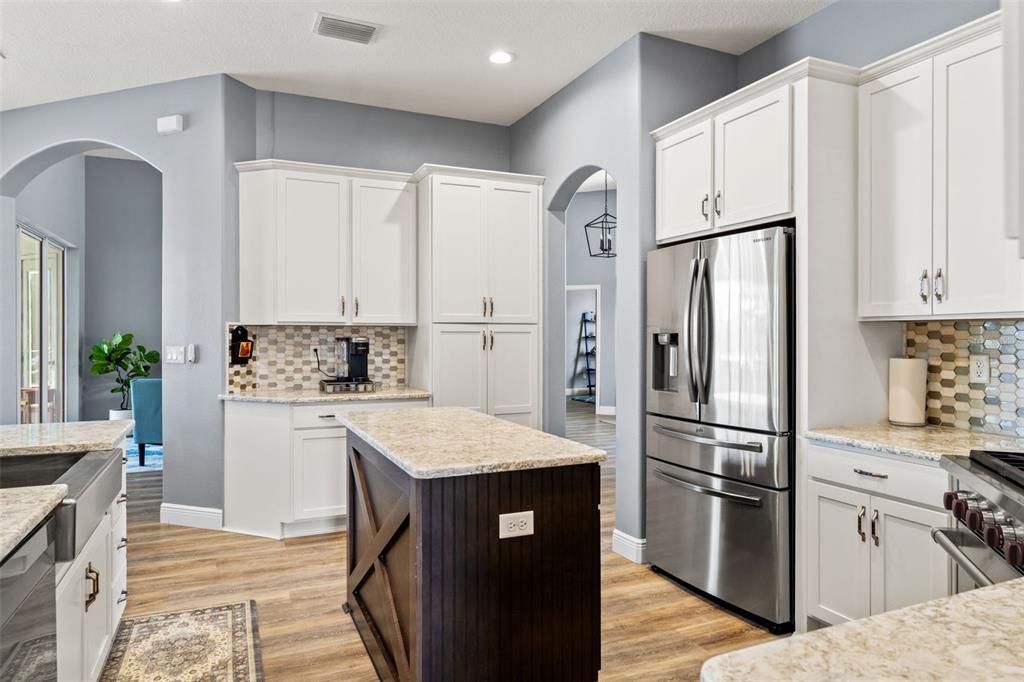 12277 Eskimo Curlew Road Weeki Wachee, FL 34614 - Photo 15 of 84 a kitchen with white cabinets and stainless steel appliances