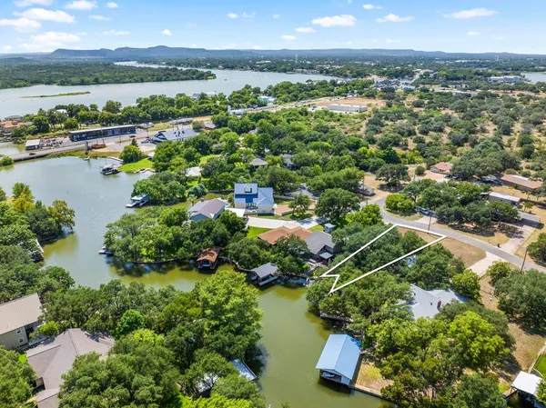 an aerial view of city and lake with trees