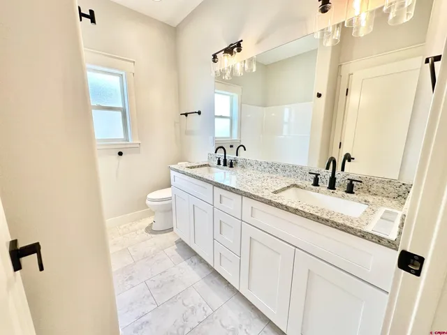 a bathroom with a granite countertop sink mirror vanity and toilet