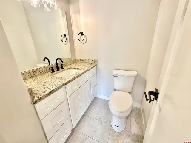 a bathroom with a granite countertop toilet and a sink