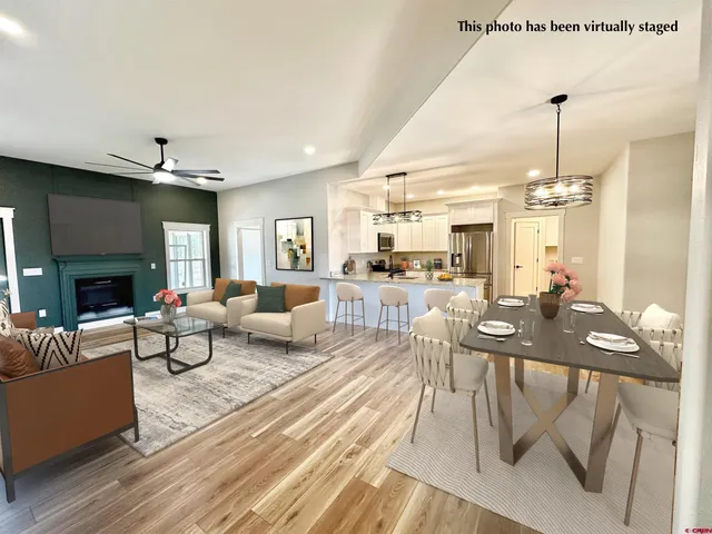 a living room with furniture a fireplace and a dining table with wooden floor