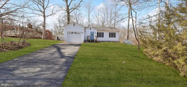 a front view of a house with yard and tree