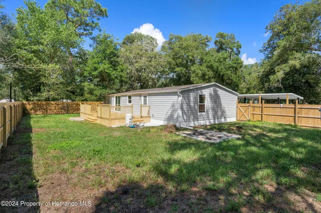 a view of a backyard with a trees and wooden fence