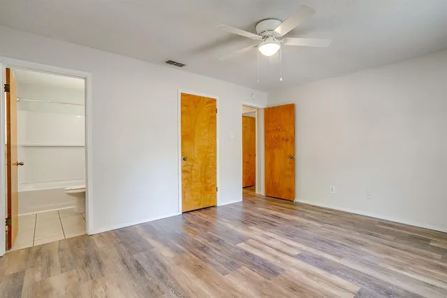 a view of empty room with wooden floor and ceiling fan