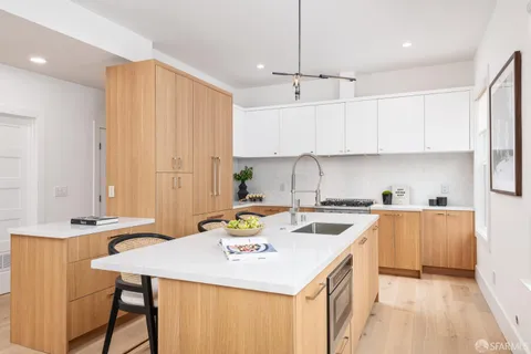 a kitchen with a stove a sink a refrigerator and white cabinets with wooden floor