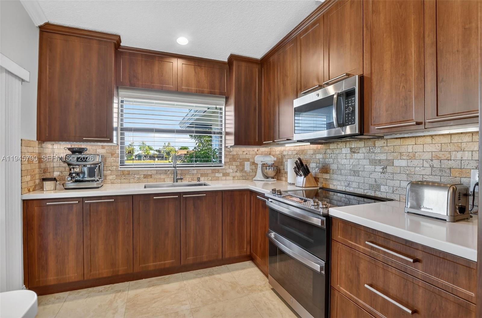 9943 Majorca Place Boca Raton, FL 33434 - Photo 19 of 48 a kitchen with stainless steel appliances granite countertop wooden cabinets a sink and a window
