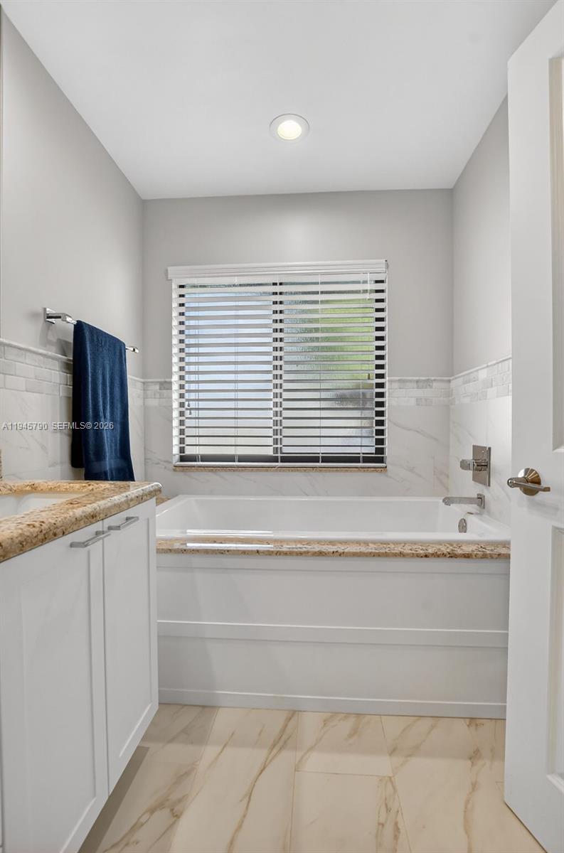 9943 Majorca Place Boca Raton, FL 33434 - Photo 33 of 48 a bathroom with a granite countertop sink and a bathtub