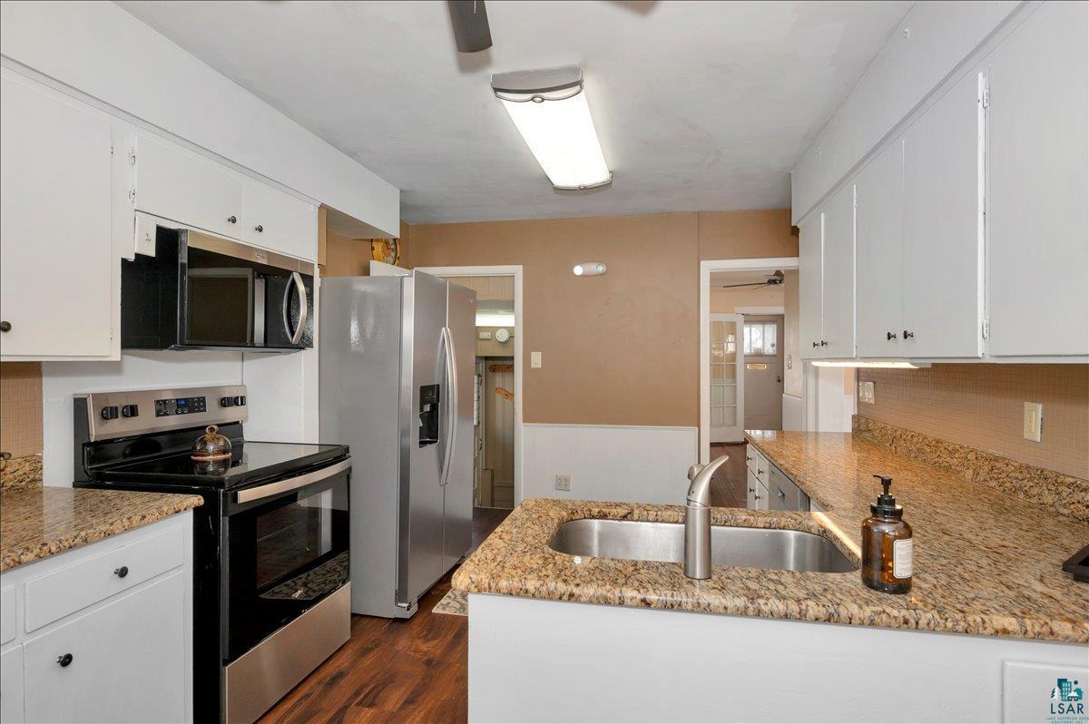 4345 West 8th Street Duluth, MN 55807 - Photo 13 of 31 Kitchen with stainless steel appliances, ceiling fan, white cabinetry, wainscoting, and dark wood finished floors