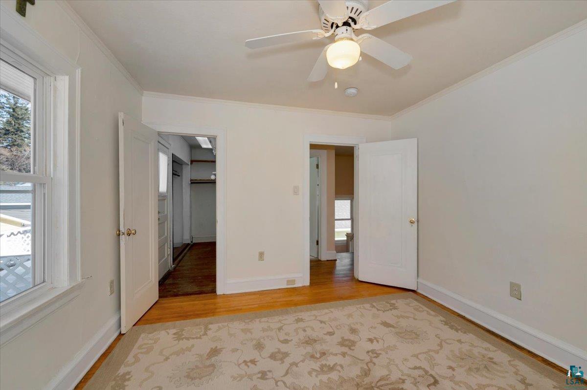 4345 West 8th Street Duluth, MN 55807 - Photo 20 of 31 Unfurnished bedroom featuring a walk in closet, light wood-style flooring, ornamental molding, and a ceiling fan