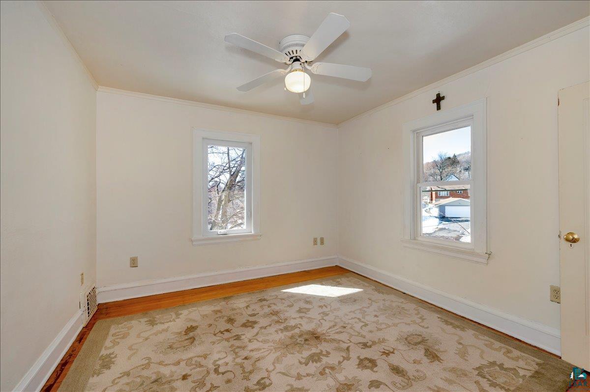 4345 West 8th Street Duluth, MN 55807 - Photo 21 of 31 Unfurnished room featuring light wood-type flooring, crown molding, and ceiling fan
