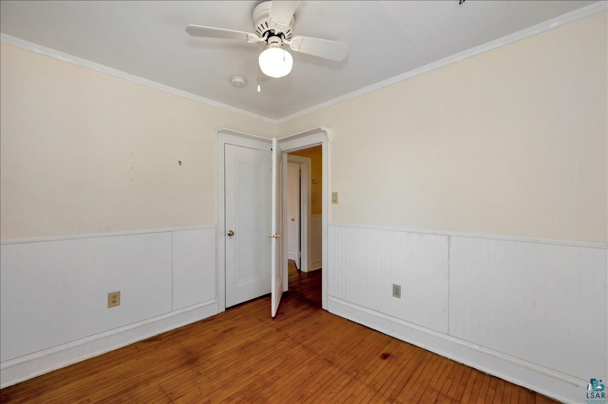 4345 West 8th Street Duluth, MN 55807 - Photo 22 of 31 Empty room featuring hardwood / wood-style flooring, crown molding, ceiling fan, and wainscoting