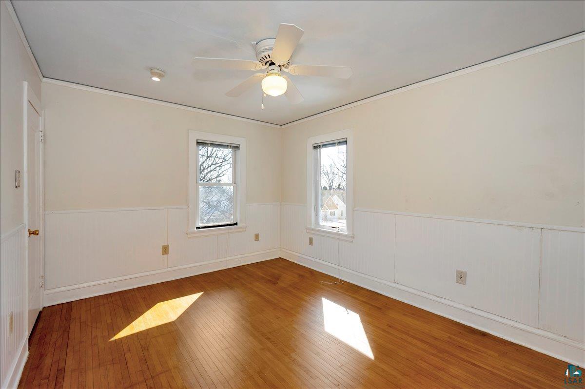 4345 West 8th Street Duluth, MN 55807 - Photo 23 of 31 Spare room featuring hardwood / wood-style flooring, ceiling fan, crown molding, and wainscoting