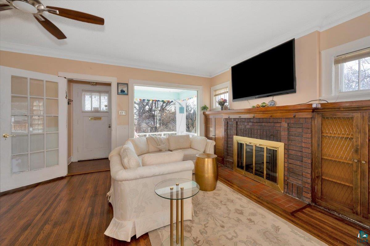 4345 West 8th Street Duluth, MN 55807 - Photo 9 of 31 Living area with plenty of natural light, wood finished floors, a ceiling fan, crown molding, and a brick fireplace