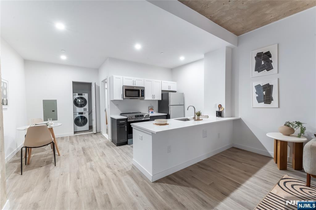 a kitchen with stainless steel appliances a stove top oven a sink dishwasher and white cabinets with wooden floor