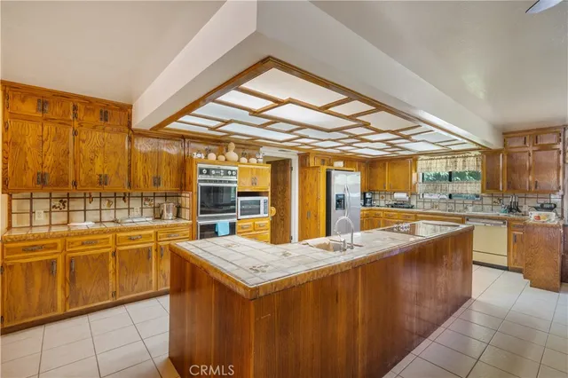 a room with stainless steel appliances kitchen island granite countertop a sink and cabinets