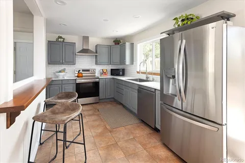 a kitchen with stainless steel appliances granite countertop a refrigerator a sink a stove and chairs