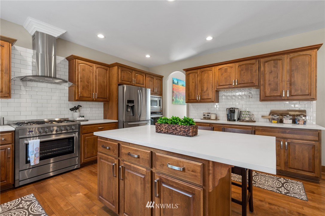 3113 223rd Street Southeast Bothell, WA 98021 - Photo 15 of 40 a kitchen with kitchen island granite countertop wooden cabinets and a stove