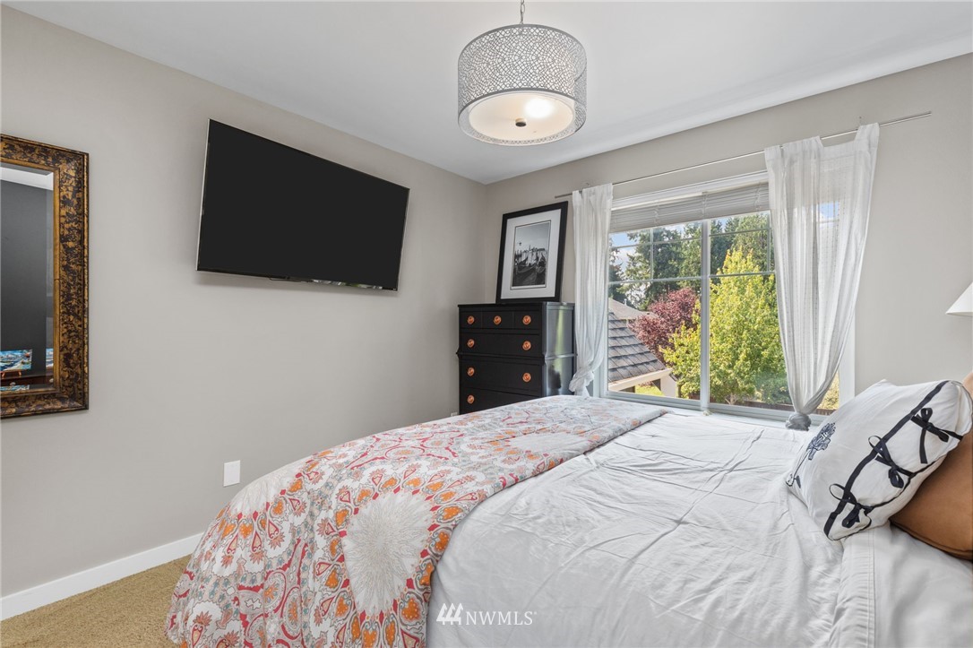 3113 223rd Street Southeast Bothell, WA 98021 - Photo 32 of 40 a bedroom with a bed and a flat tv screen on dresser