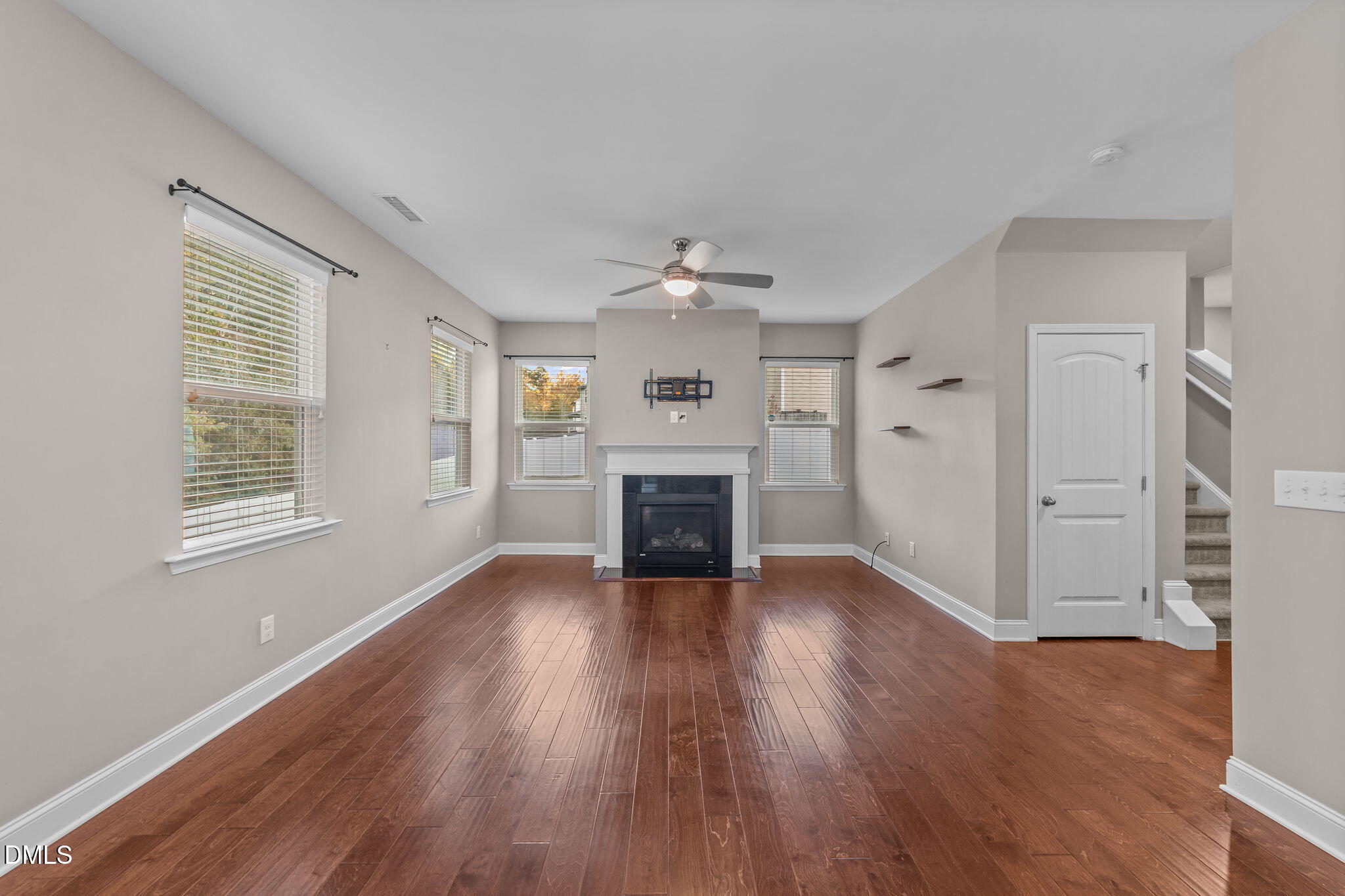 26 Mint Julip Circle Clayton, NC 27527 - Photo 9 of 46 an empty room with windows a fireplace a ceiling fan and wooden floor