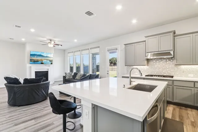 a open kitchen with stainless steel appliances granite countertop a sink a stove and chairs with wooden floor