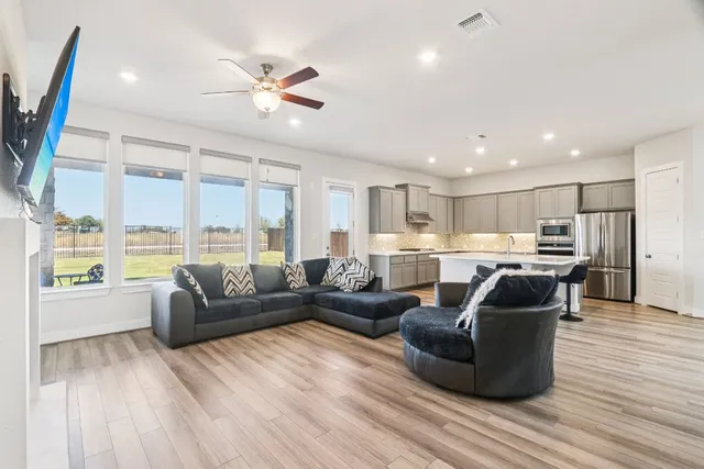 a kitchen with a sink a stove and chairs with wooden floor