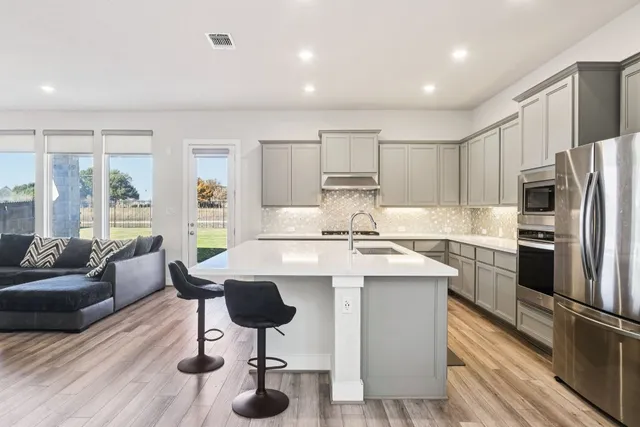 a kitchen with a refrigerator a stove a sink and chairs