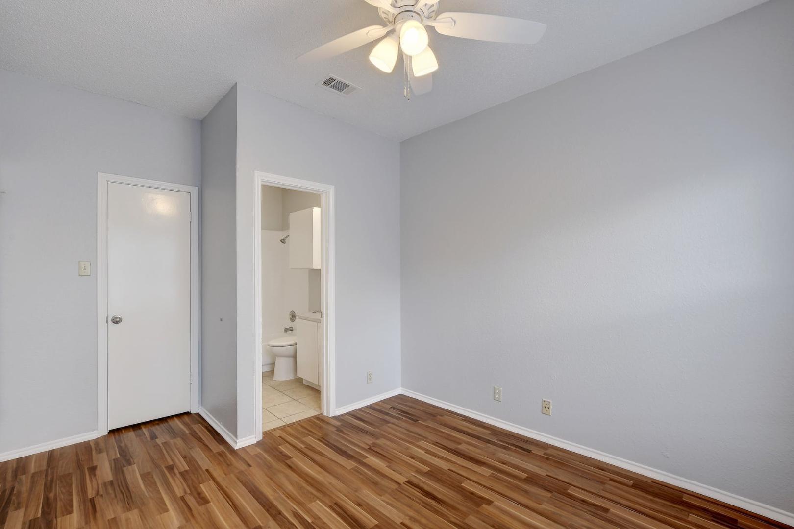 2804 Rio Grande Street, Unit 310 Austin, TX 78705 - Photo 13 of 22 A well-lit bedroom with rich wood flooring leads to an adjoining bathroom.