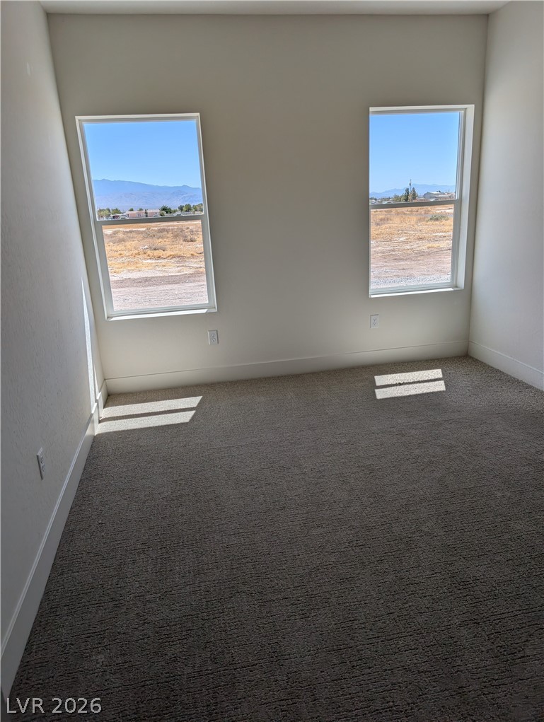 4670 Medicine Man Road Pahrump, NV 89048 - Photo 23 of 36 A quiet space with soft carpet, bathed in sunlight, overlooks a scenic mountain backdrop.