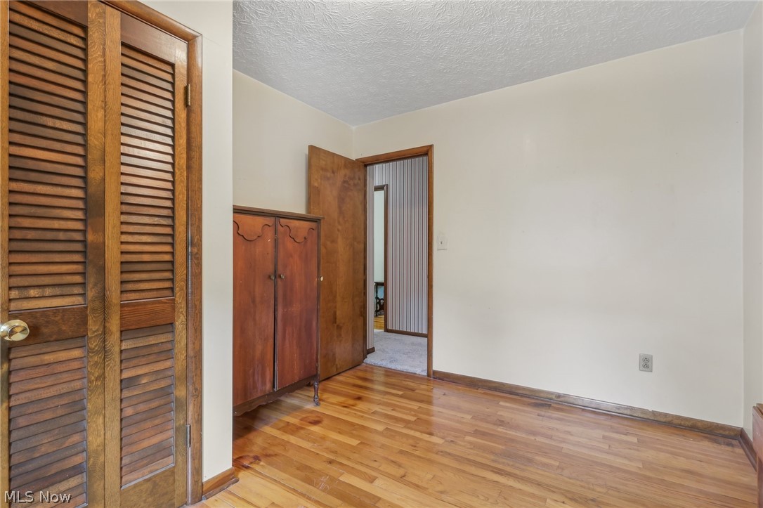 1762 Stonehaven Road Madison, OH 44057 - Photo 15 of 36 Unfurnished bedroom featuring light wood-type flooring, a closet, and a textured ceiling