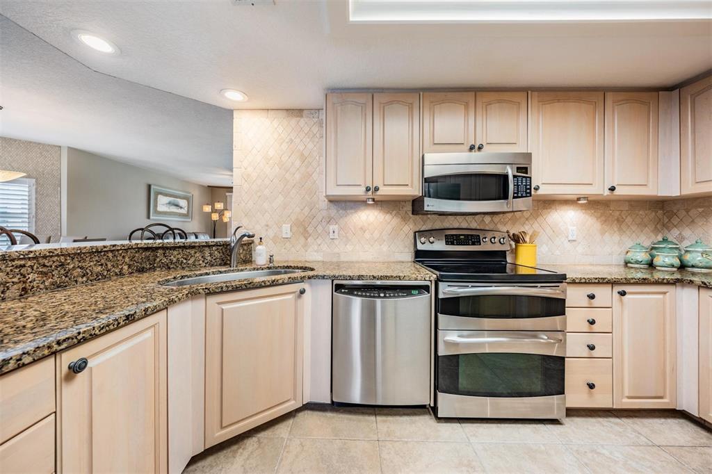 399 150th Avenue, Unit 315 Madeira Beach, FL 33708 - Photo 15 of 53 a kitchen with granite countertop white cabinets and stainless steel appliances