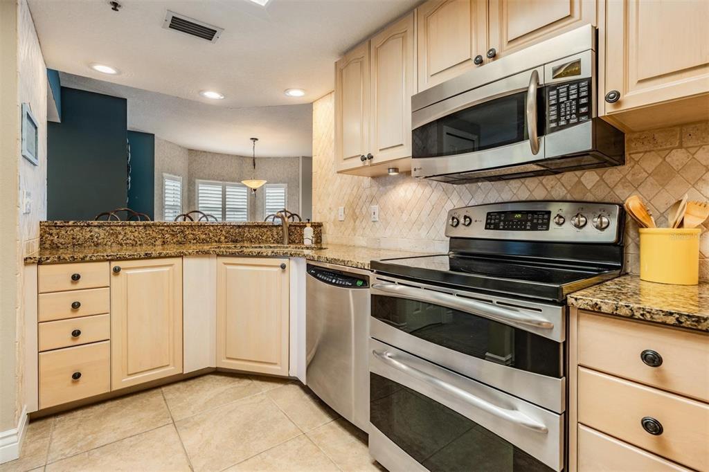 399 150th Avenue, Unit 315 Madeira Beach, FL 33708 - Photo 16 of 53 a kitchen with granite countertop cabinets stainless steel appliances and a counter space