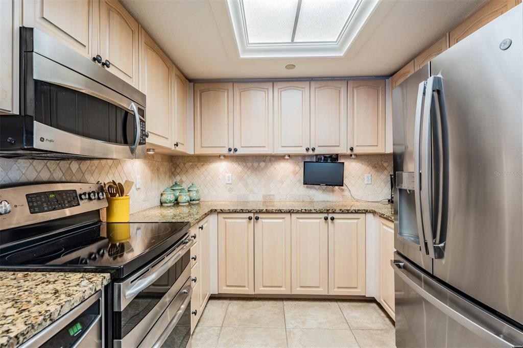 399 150th Avenue, Unit 315 Madeira Beach, FL 33708 - Photo 17 of 53 a kitchen with granite countertop a refrigerator stove and microwave