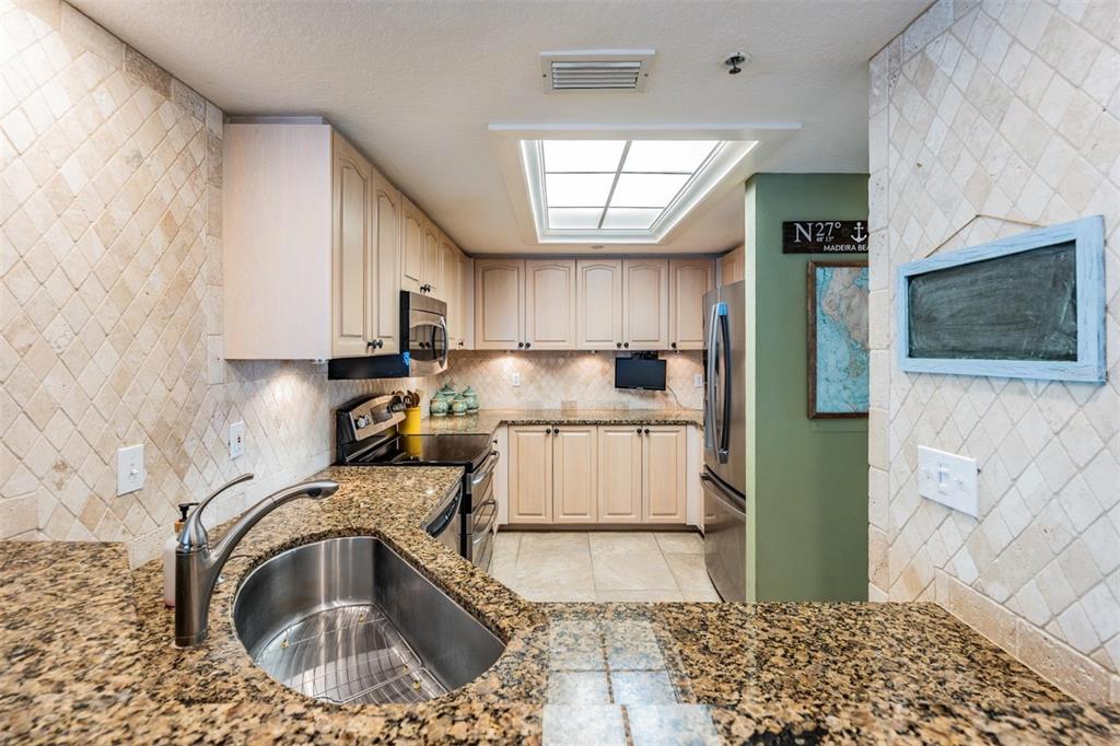 399 150th Avenue, Unit 315 Madeira Beach, FL 33708 - Photo 19 of 53 a kitchen with stainless steel appliances granite countertop a sink a refrigerator and a stove