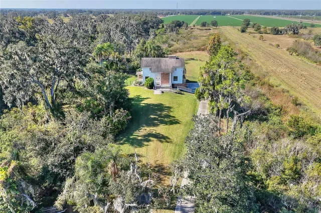 an aerial view of residential houses with outdoor space and trees all around