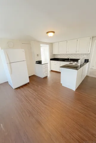 a kitchen with granite countertop white cabinets and white appliances