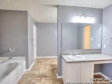 a bathroom with a tub sink and mirror