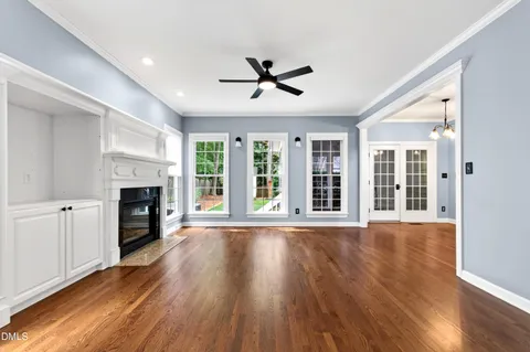 a view of an empty room with wooden floor and window