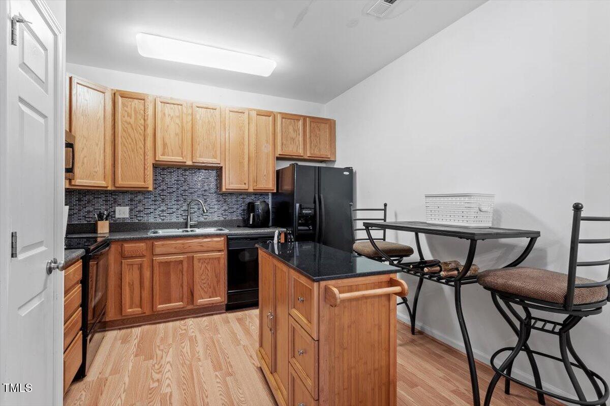 300 Gilman Lane, Unit 101 Raleigh, NC 27610 - Photo 11 of 25 a kitchen with stainless steel appliances granite countertop a stove top oven a sink dishwasher a dining table and chairs with wooden floor
