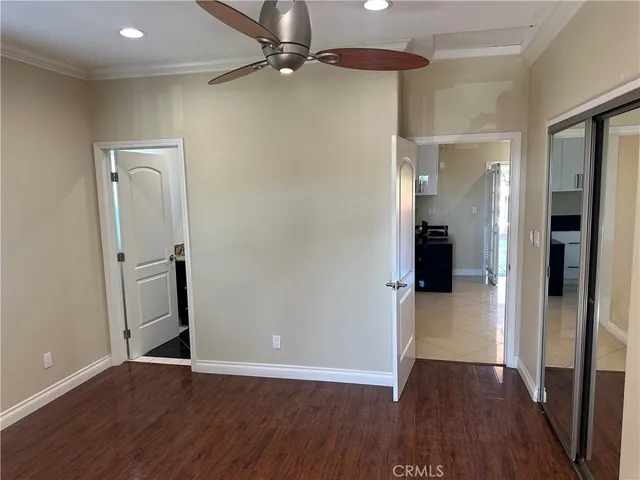 an empty room with wooden floor and a ceiling fan