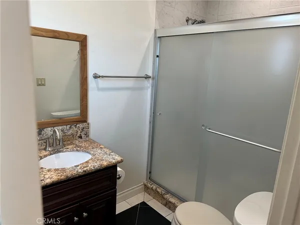 a bathroom with a granite countertop sink toilet and a mirror