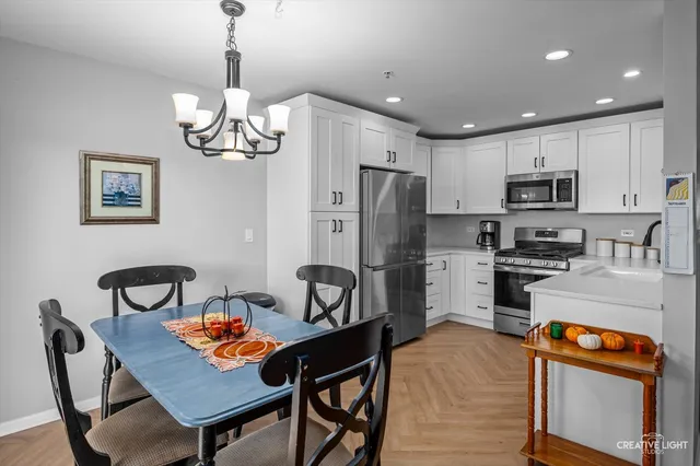 a kitchen with stainless steel appliances granite countertop a dining table chairs refrigerator and microwave