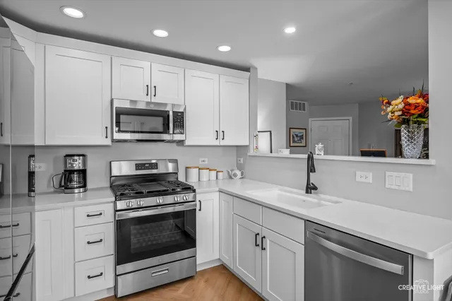a kitchen with granite countertop a sink stainless steel appliances and cabinets