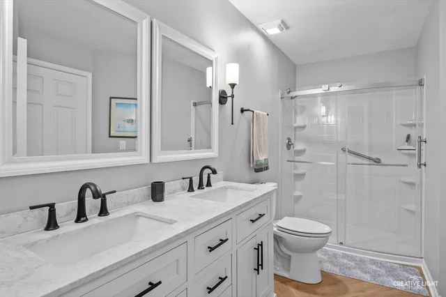 a bathroom with a double vanity sink toilet and shower