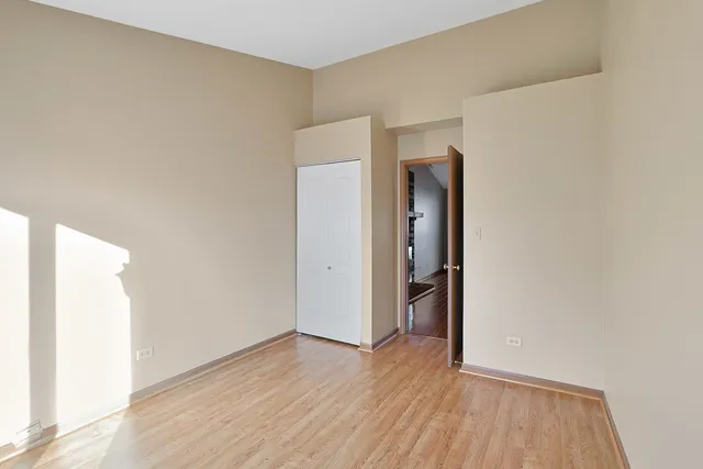 a view of an empty room with wooden floor and closet